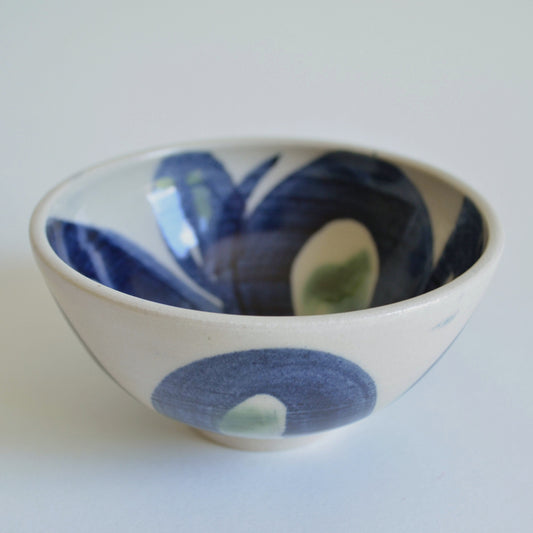 Ceramic bowl with blue and green abstract design on a white background